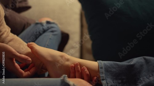 Mom hands tickling kid foot indoors. Unknown mother child having tender moment.