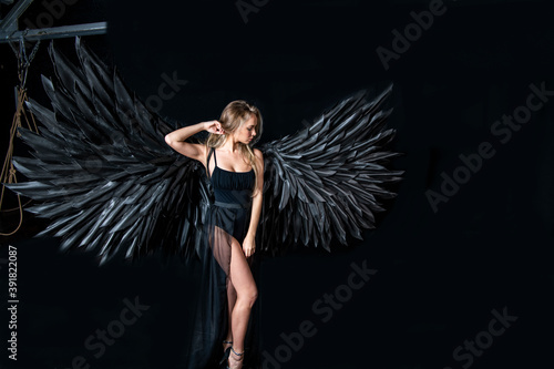 beautiful blonde girl in a black suit with black wings on a black background