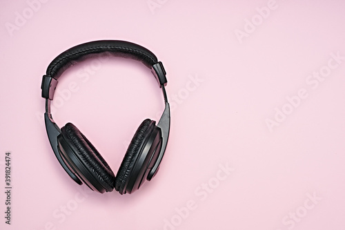 Large, black headphones lie on a colored background. Device for individual listening to music.