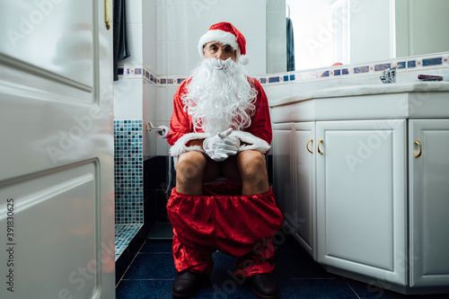 Santa Claus sitting in the toilet bowl pooping