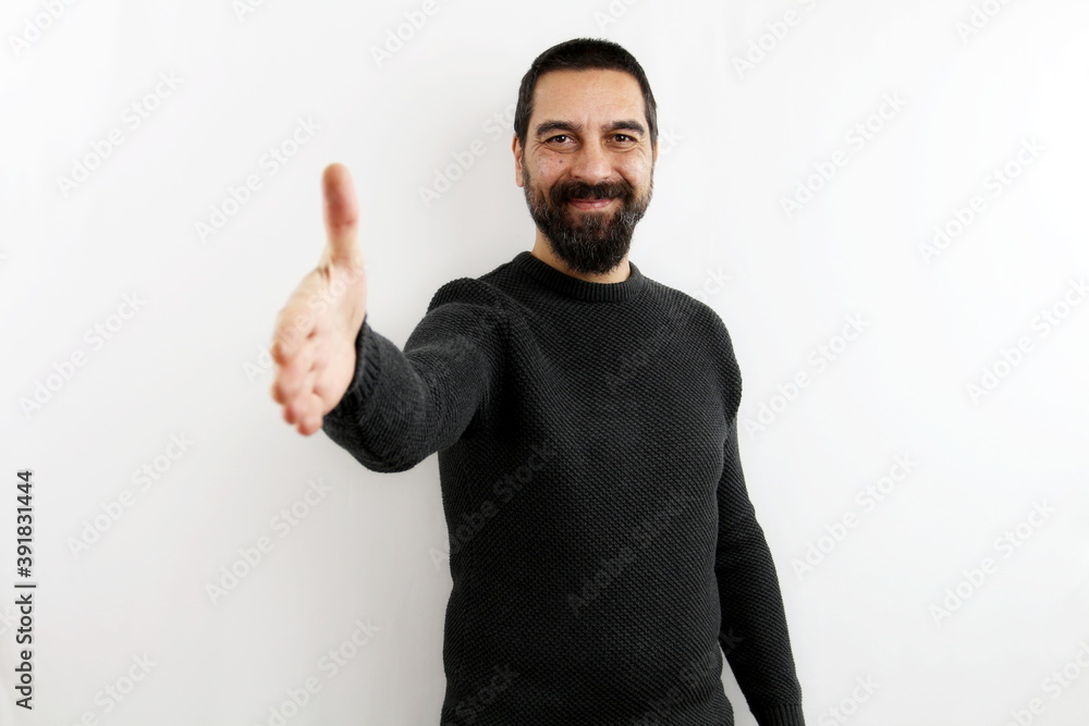 Smiling young bearded man on isolated white background smiling stretches out his arm by opening his hand in greeting. Greet, shake hands Smiling young bearded man on isolated white background smiling stretches out his arm by opening his hand in greeting. Greet, shake hands