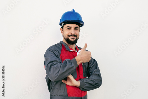 Attractive hardworking man looks at camera and smiles raising his thumb