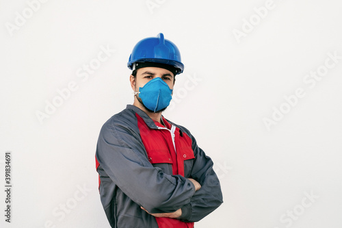 Attractive worker man with face mask for protection looks at camera