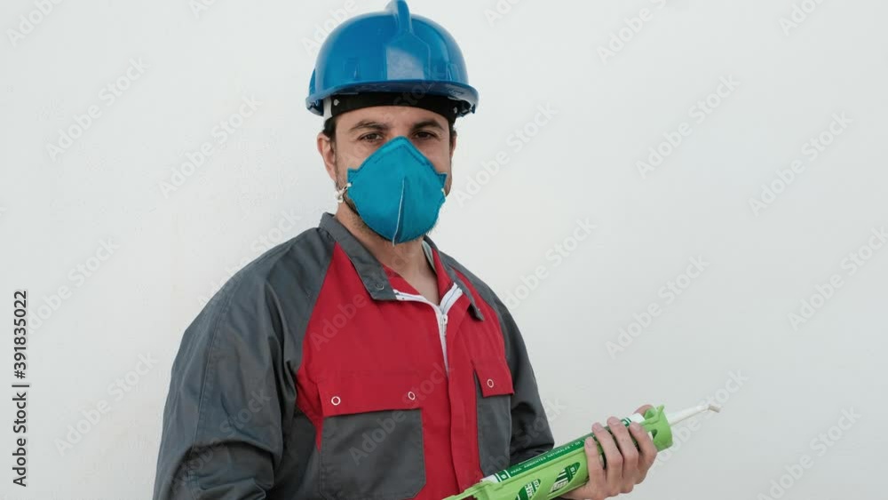 Worker man with silicone gun and protective mask ready to work repairing joints Worker man with silicone gun and protective mask ready to work repairing joints