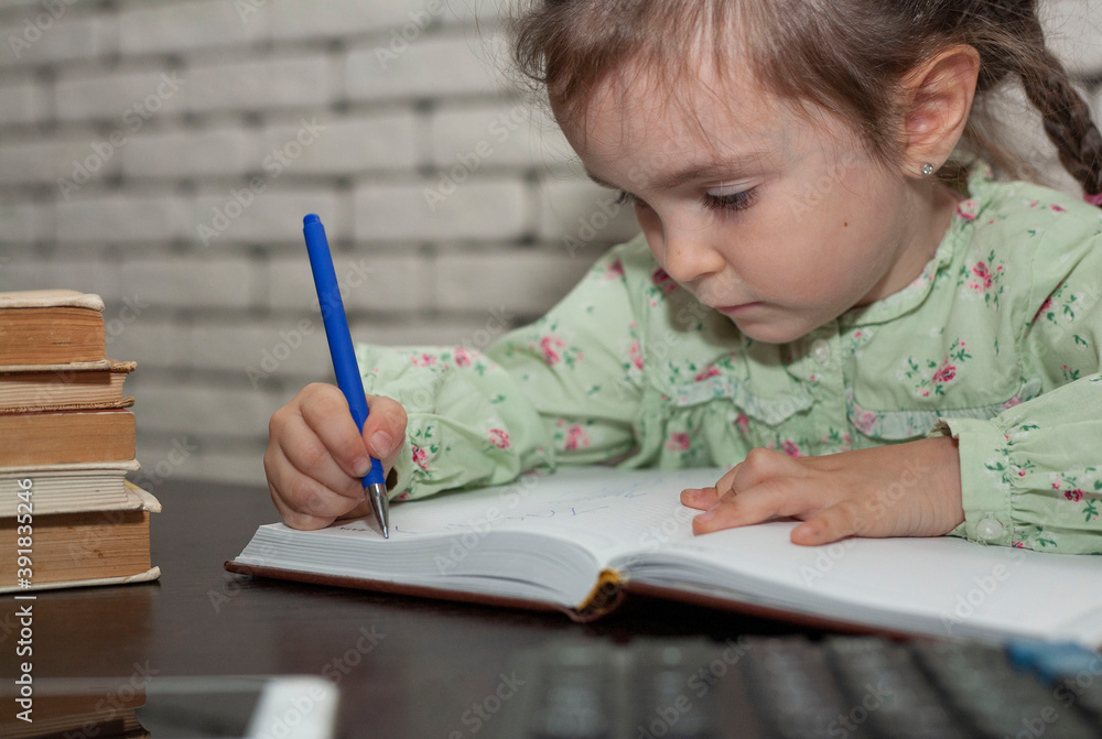 Little girl works in the office. The child takes notes in a notebook at the desk. Little girl works in the office. The child takes notes in a notebook at the desk.