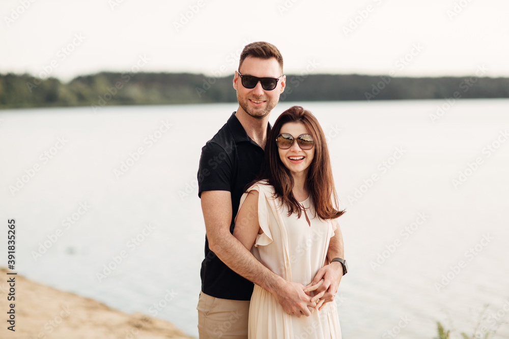 Romantic couple is hugging outdoors. elegant and stylish woman and man in love are walking along the lake. Happy moments together. love story