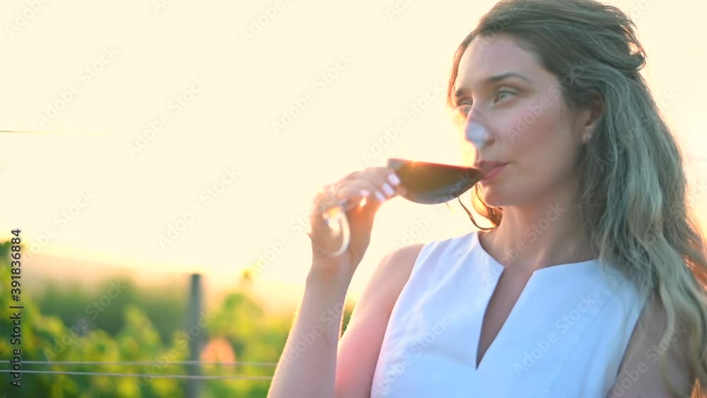 Woman wearing white dress drinking red wine in a glass at sunset in Moldova Woman wearing white dress drinking red wine in a glass at sunset in Moldova