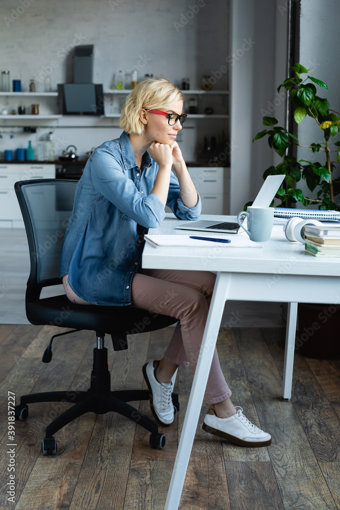 full length of young blonde woman in eyeglasses working from home - obrazy, fototapety, plakaty 