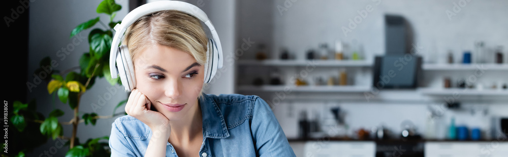 young blonde woman in headphones leaning on hand and looking down, banner - obrazy, fototapety, plakaty 