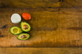 Aguacate, tomate y cebolla ingredientes para hacer guacamole sobre una mesa de madera