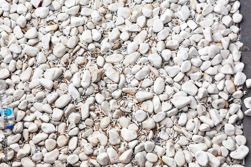 Cigarette butts are in white pebbles, small parts of a cigarette that is left after smoking, background Cigarette butts are in white pebbles, small parts of a cigarette that is left after smoking, background