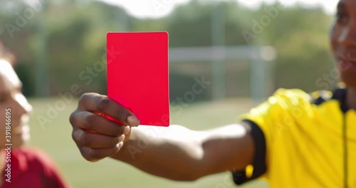 Female referee holding red card to soccer player