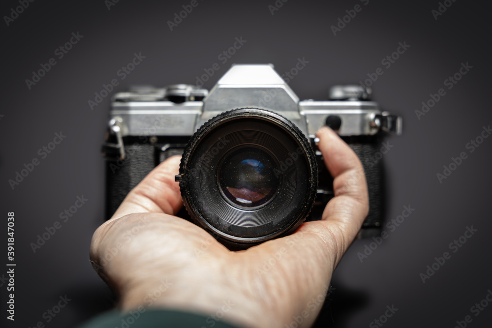 Titel: Old analog camera from the front in the hands of a photographer