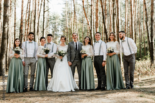 newlyweds with friends and friendships,witnesses at the wedding,wedding day of the bride and groom,cheerful groom with the bride and a group of witnesses are photographed in the forest,