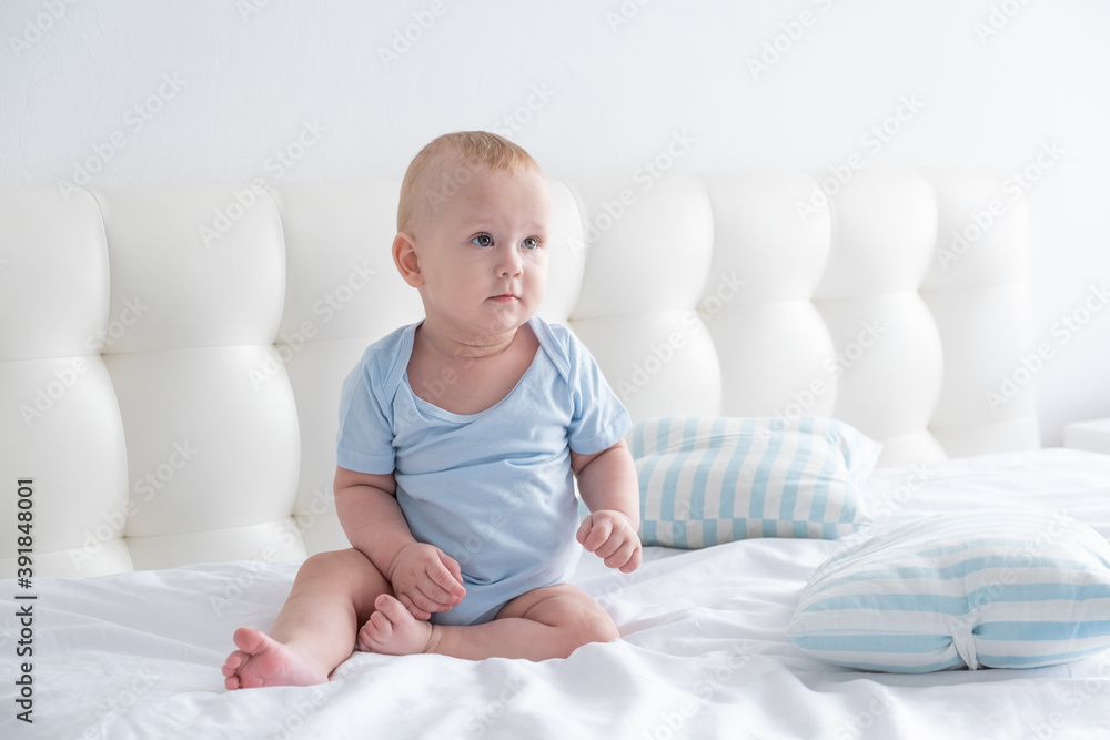Cute baby boy sitting in the bed at home. bedding for children. Cute baby boy sitting in the bed at home. bedding for children.