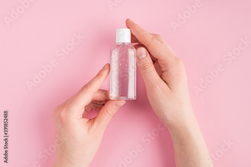 Top above overhead close up pov first person view photo of female holding gel sanitizer isolated on pink pastel background with copyspace