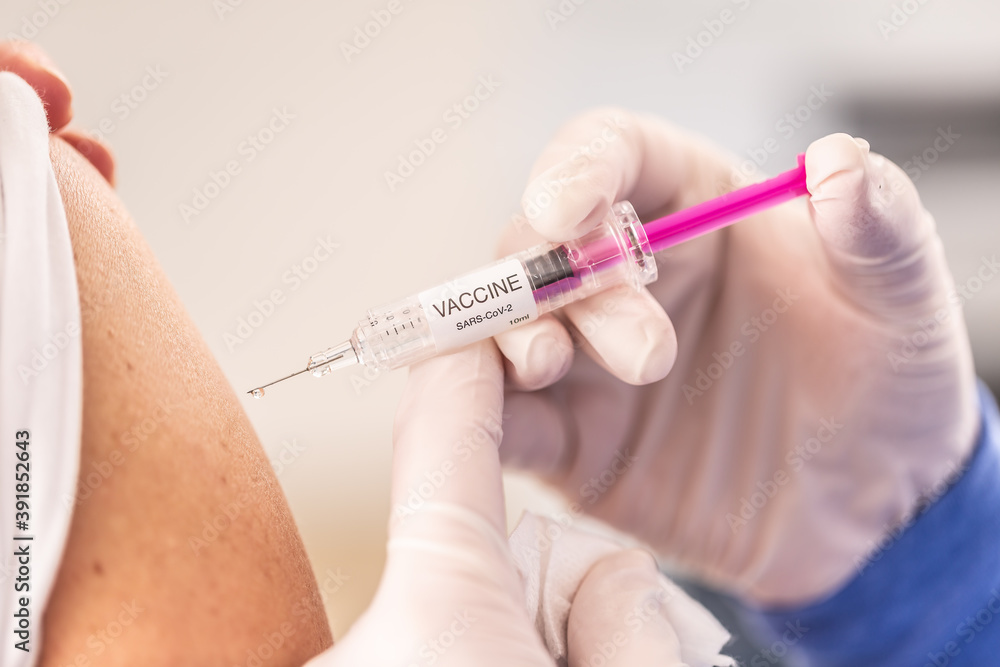 Detail of an injection of a SARS-CoV-2 vaccine being shot to a shoulder of a patient Detail of an injection of a SARS-CoV-2 vaccine being shot to a shoulder of a patient