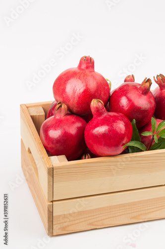 Pomegranate fruits in wooden box on white background