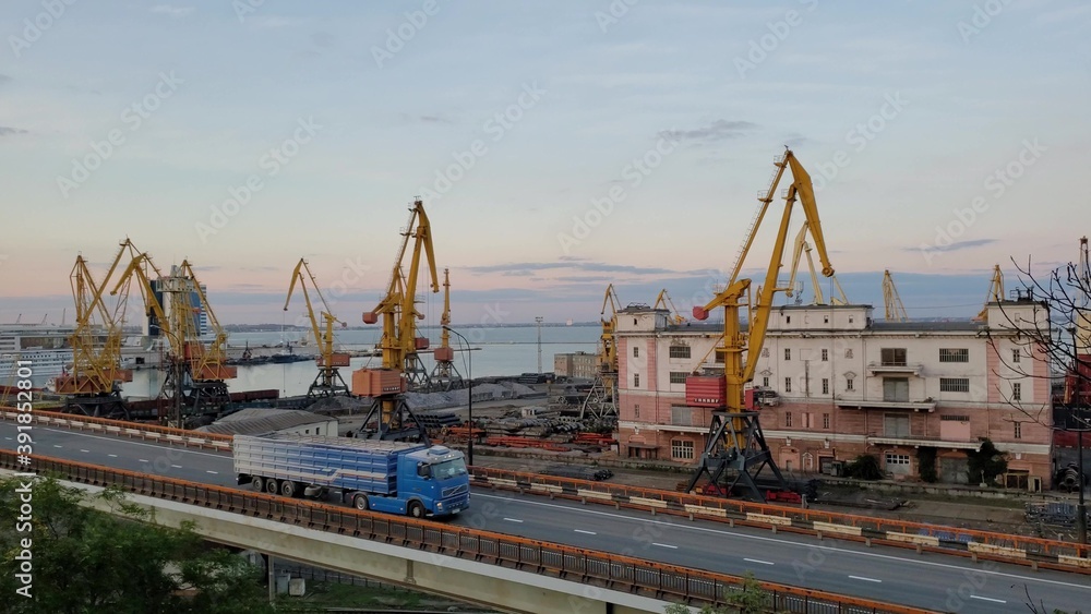 Industrial port landscape with cargo cranes and cargo vehicle traffic by overpass