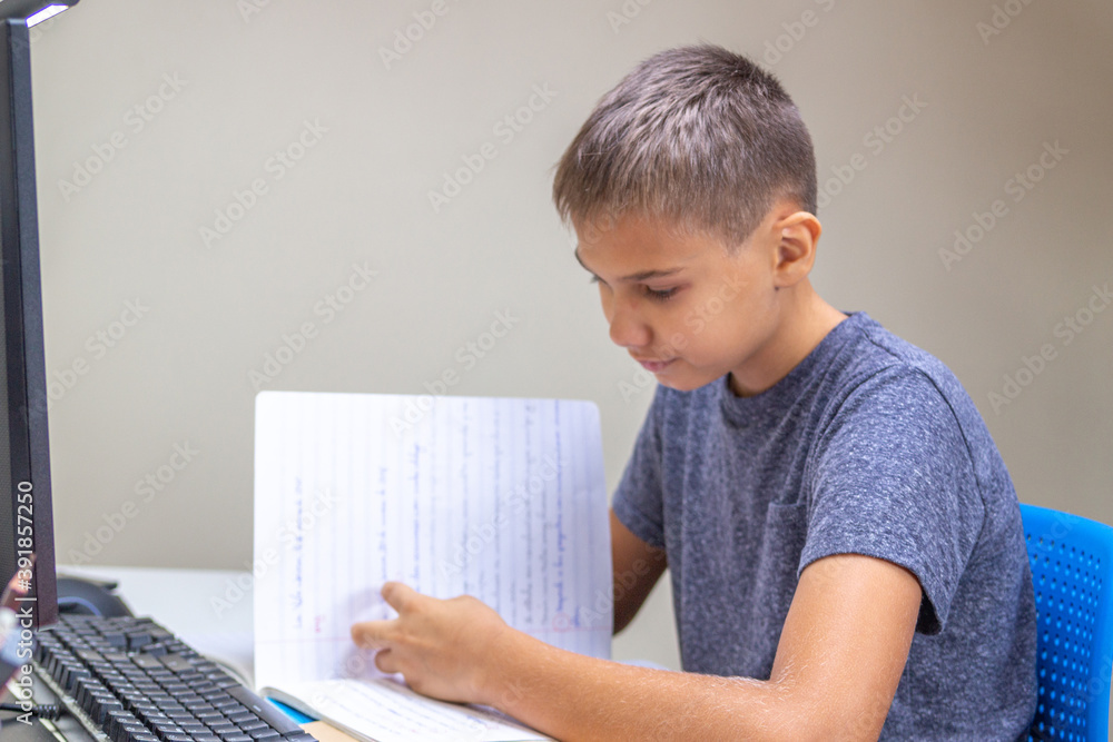 Teenage boy learning, turning pages of notebook, doing homework, preparing for online lesson. Technology, online learning, remote education at home Teenage boy learning, turning pages of notebook, doing homework, preparing for online lesson. Technology, online learning, remote education at home
