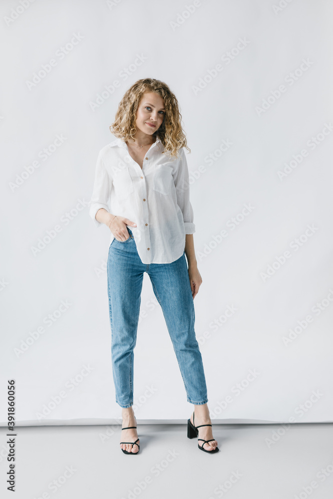 Portrait of a beautiful girl in a white shirt and jeans on a white background. Lifestyle Portrait of a beautiful girl in a white shirt and jeans on a white background. Lifestyle