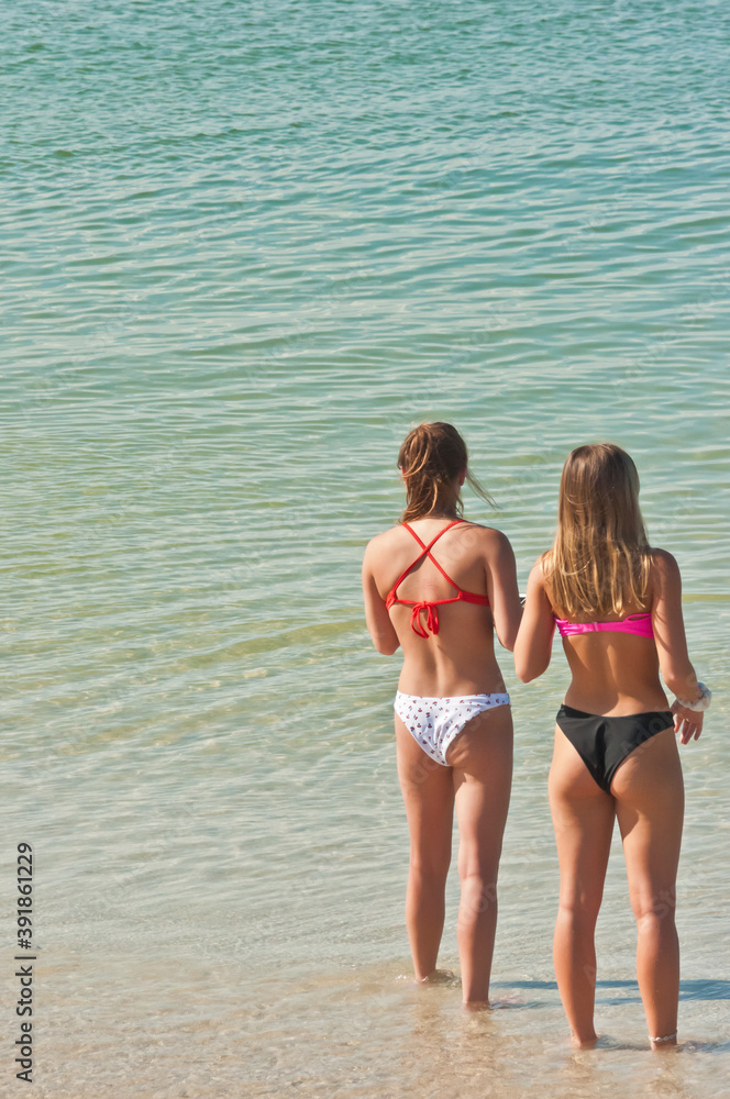 Two female teenagers in bikinis on the beach Stock Photo by