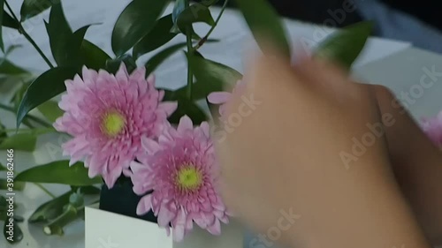 The girl creates ikebana from autumn chrysanthemums and green twigs.