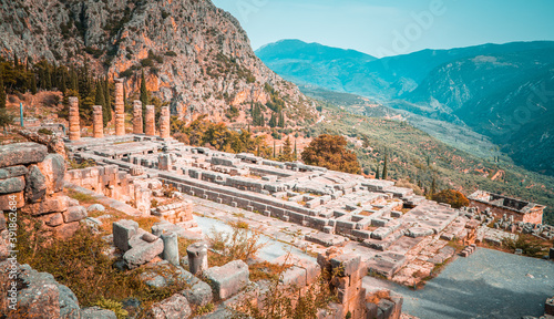 Panoramic view of the Temple of Apollo and the Treasury of the Athenians with mountains in the background in Delphi, Greece