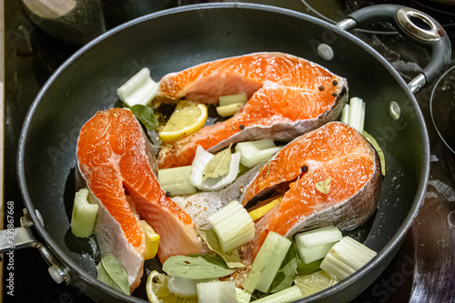 Salmon steaks are fried in a pan with celery and spices