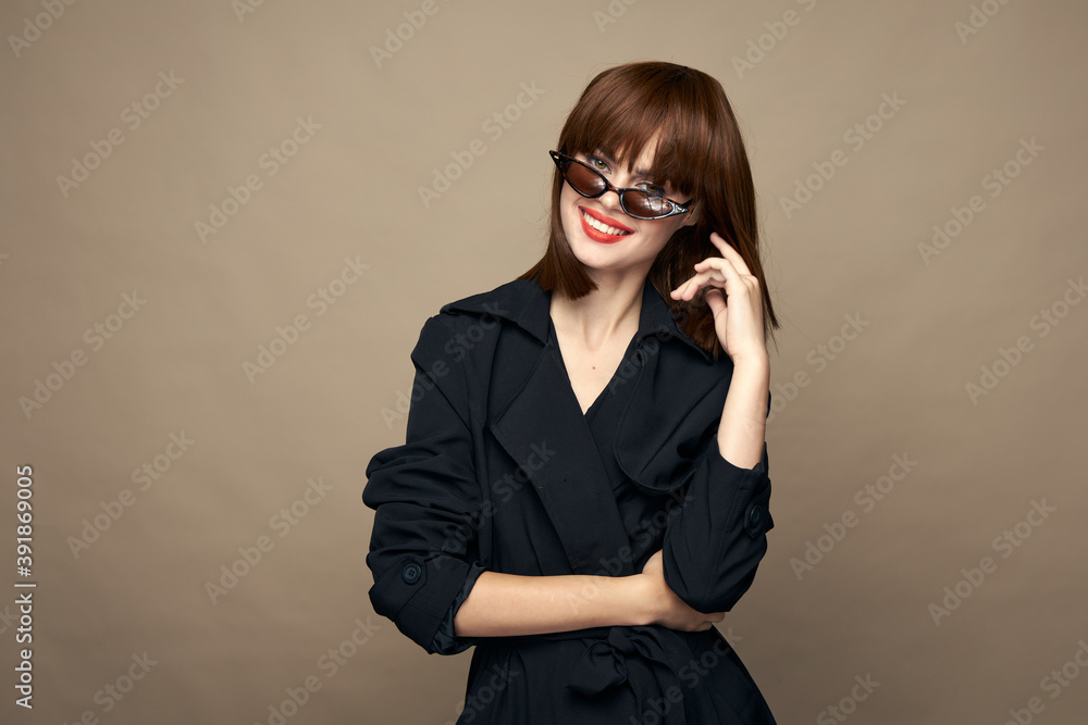 Sexy woman coat with belt bright makeup having fun on a beige background Sexy woman coat with belt bright makeup having fun on a beige background