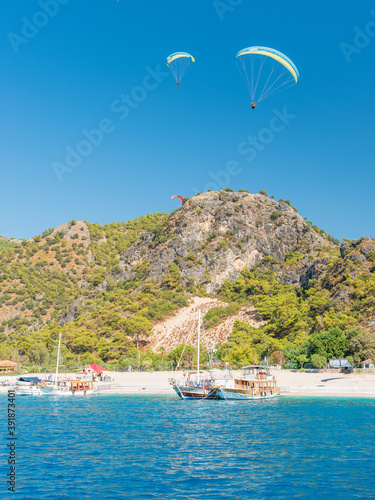 two paraglides above yacht on the beach