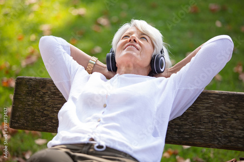 Photography happy senior woman listening music with headphones and smartphone