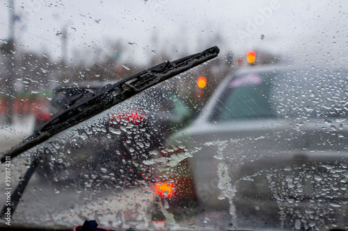 very poor view of the road, through a dirty windshield covered with ice, snow and water, against a blurred foreground and background with bokeh effect