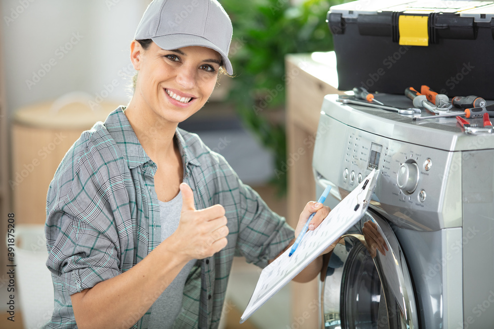 young woman repairing washing machine - obrazy, fototapety, plakaty 