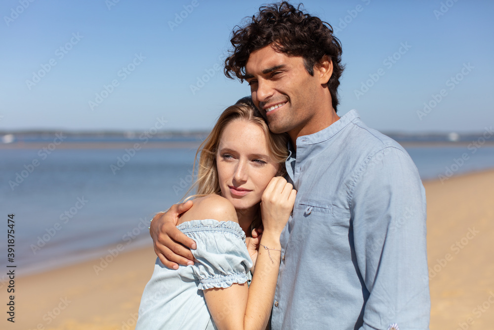 attractive couple snuggled together on the beach