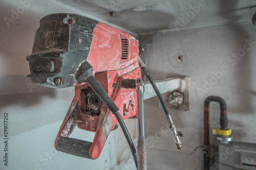 Machine for drilling holes in hthe concrete wall. Red professional drill for making holes in the walls. Back view. photo