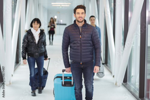 people with suitcase in airport walking in corridor