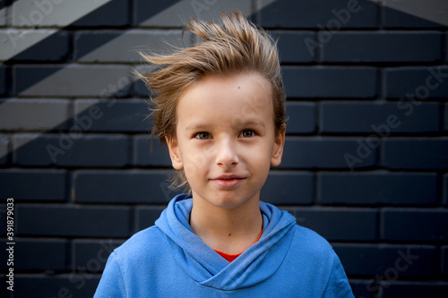 Funny portrait of a blonde caucasian boy whose hair rises and flies in the wind. Looks at the camera © Svetlana Glazkova