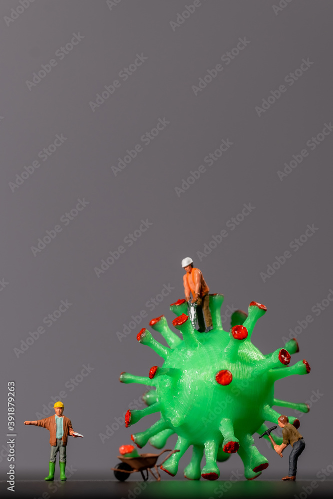 Miniature workers take a sample from a viral model, on a white background close-up. Taking an analysis For the covid-19 test. Miniature models of people destroy and investigate the virus. Macro virus.
