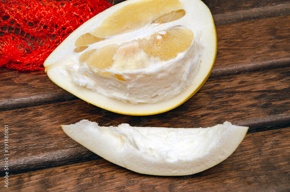 A half of pomelo and it's cut pieces on wooden background with green leafs, cut pomelo close up A half of pomelo and it's cut pieces on wooden background with green leafs, cut pomelo close up