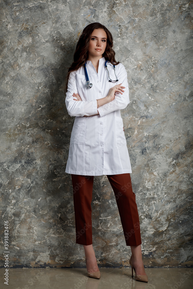 Tell me about your illnesses. Portrait of a beautiful girl with long wavy hair who stands in a white medical coat with a stethoscope. Tell me about your illnesses. Portrait of a beautiful girl with long wavy hair who stands in a white medical coat with a stethoscope.