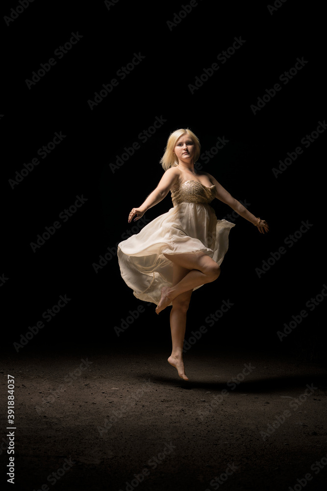 Ballerina is dancing in a white dress. Girl dancer is spinning on one leg. Young white girl jumped in dance