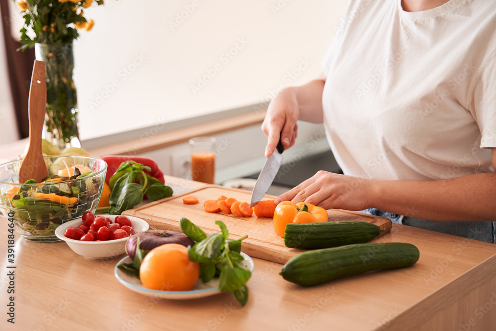 Woman chopping carrot with a knife
