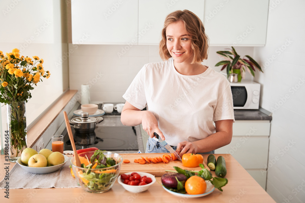 Woman chopping carrot at the wooden board Woman chopping carrot at the wooden board