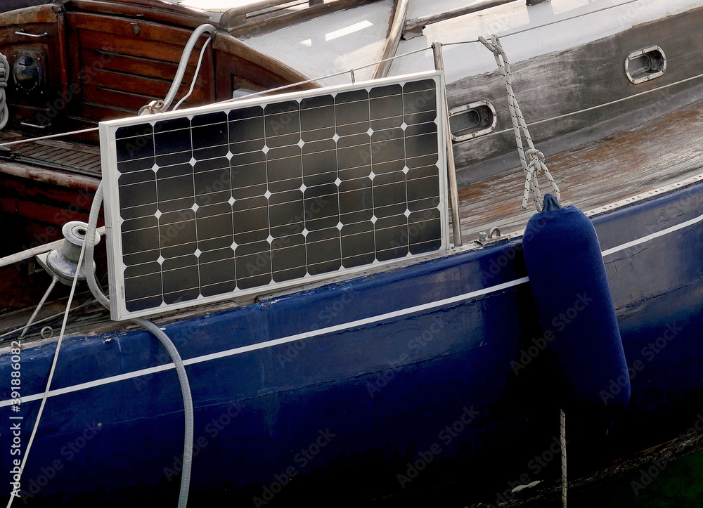 Un pannello solare montato su una barca a vela di legno con lo scafo blu. Un pannello solare montato su una barca a vela di legno con lo scafo blu.