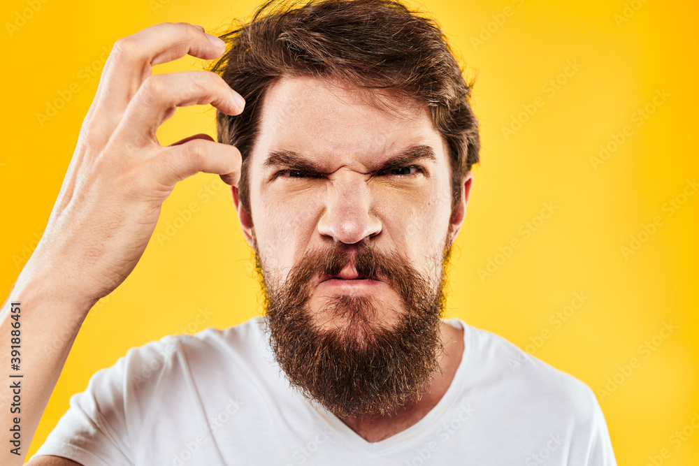 Obraz premium emotional bearded man gesturing with hands aggression discontent close-up yellow background