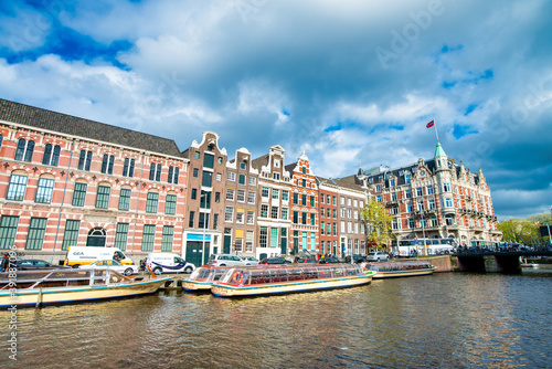 AMSTERDAM, THE NETHERLANDS - APRIL 25, 2015: Traditional houses and buildings on the canal with boats on the water