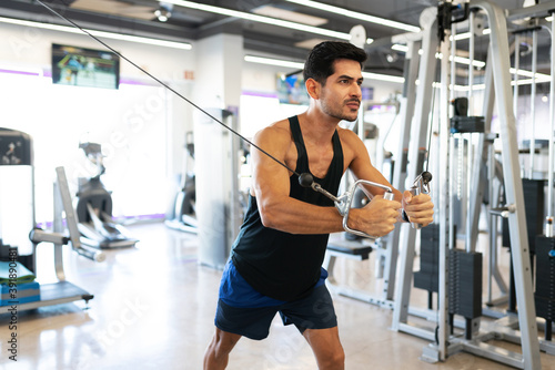 Fit man in his 20s using a cable crossover machine