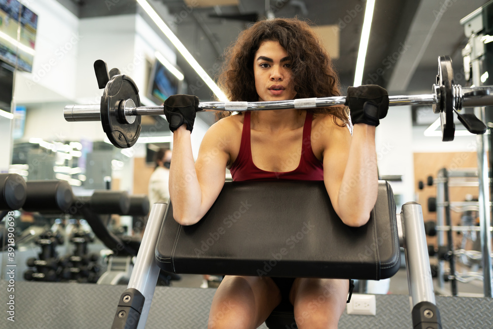 Latin woman making eye contact and lifting weights