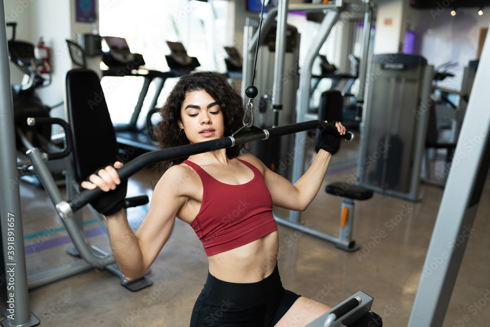 Fototapeta premium Pretty hispanic woman handling a gym machine